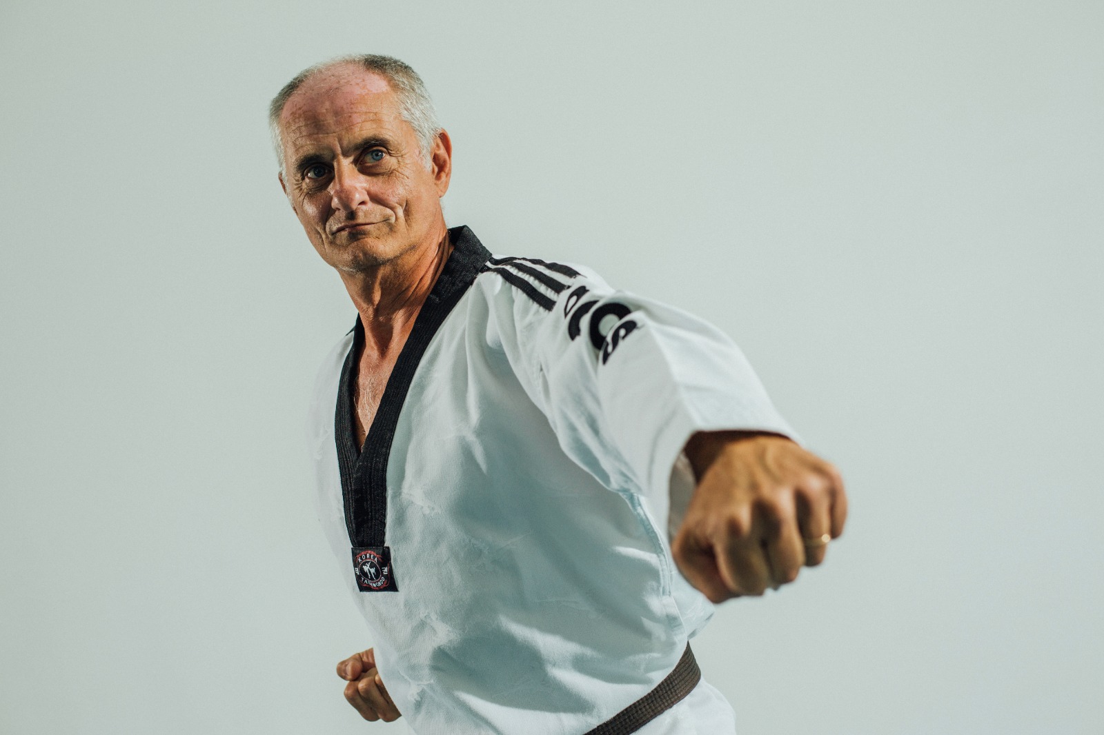 Foto di un signore anziano che fa una forma di Taekwondo